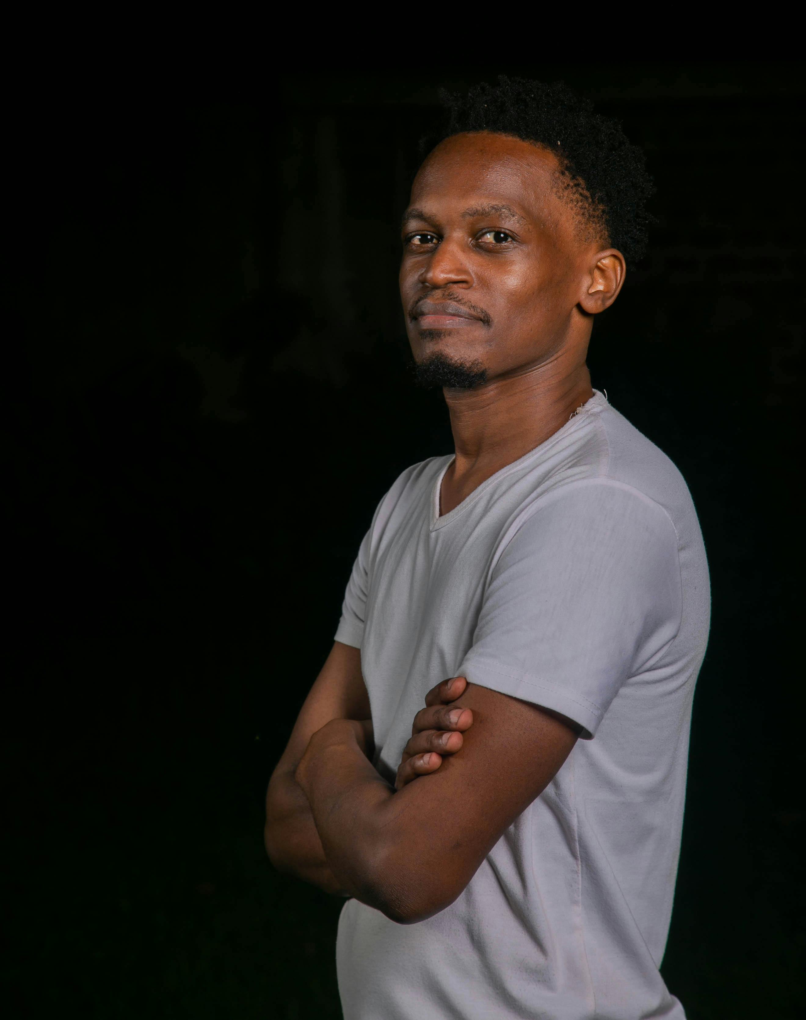 bezplatná Portrét sebevědomého mladého muže v ležérní bílé košili na tmavém pozadí. Základová fotografie