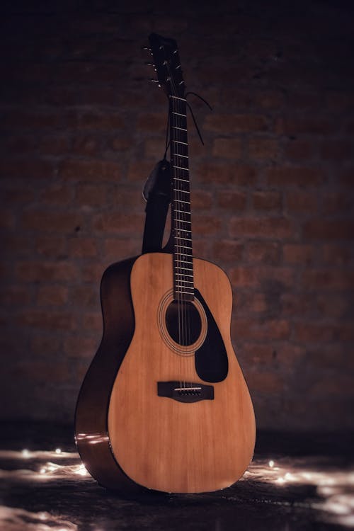 Акустическая гитара на коричневой кирпичной стене