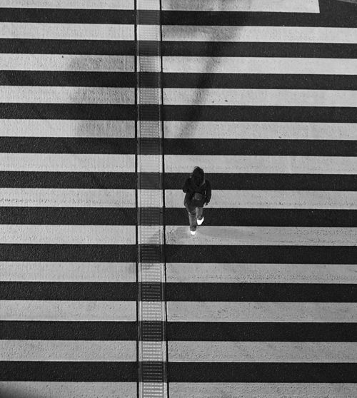 Free Monochrome aerial shot of a person crossing a zebra-striped crosswalk in Tokyo. Stock Photo