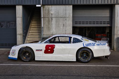 Free White race car parked outdoors near a garage on a sunny day. Stock Photo