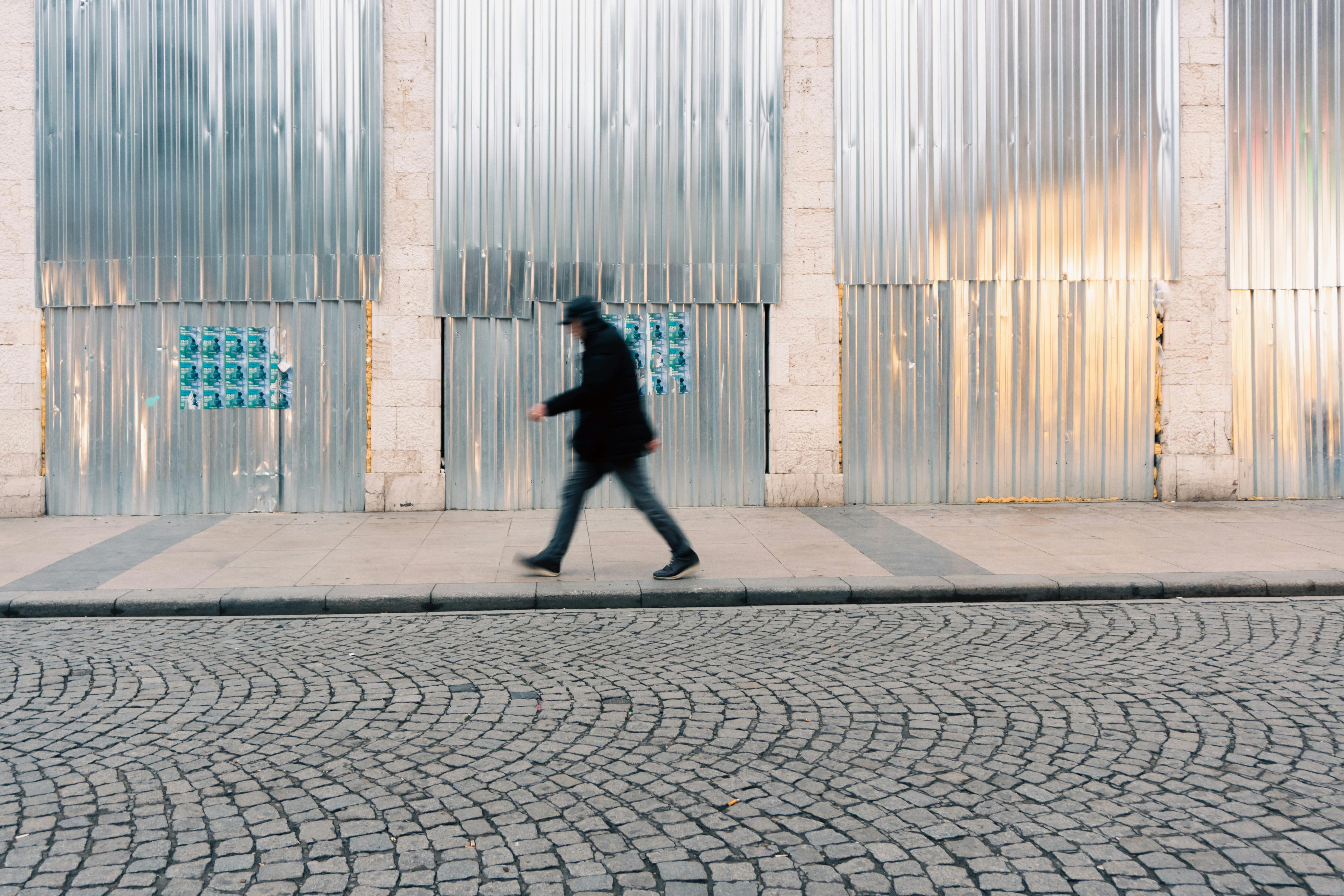 Безкоштовне Розмитий рух чоловіка, який проходить повз гофрований металевий фасад у Стамбулі на заході сонця стокове фото