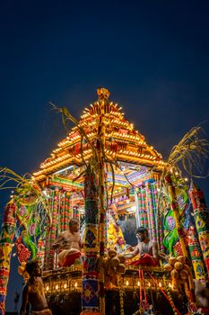 Colorful Hindu temple chariot festival with participants at night.