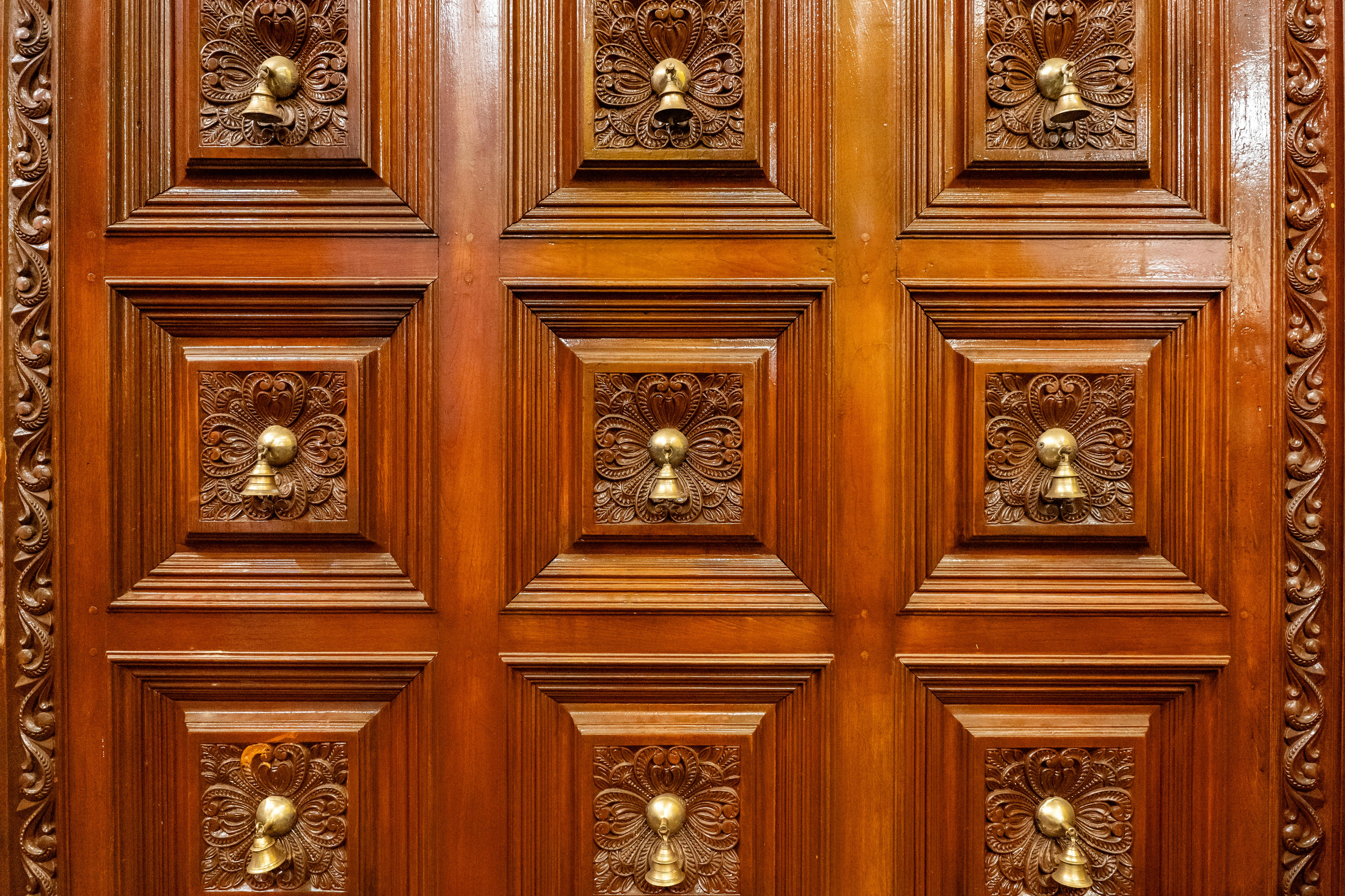 Безкоштовне Деталізовані дерев'яні двері з вишуканим різьбленням та латунними молотками, що демонструють майстерність та елегантність дизайну. стокове фото