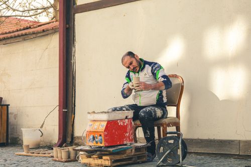 Free A potter skillfully shapes clay pottery in an outdoor studio in Kütahya, Türkiye. Stock Photo