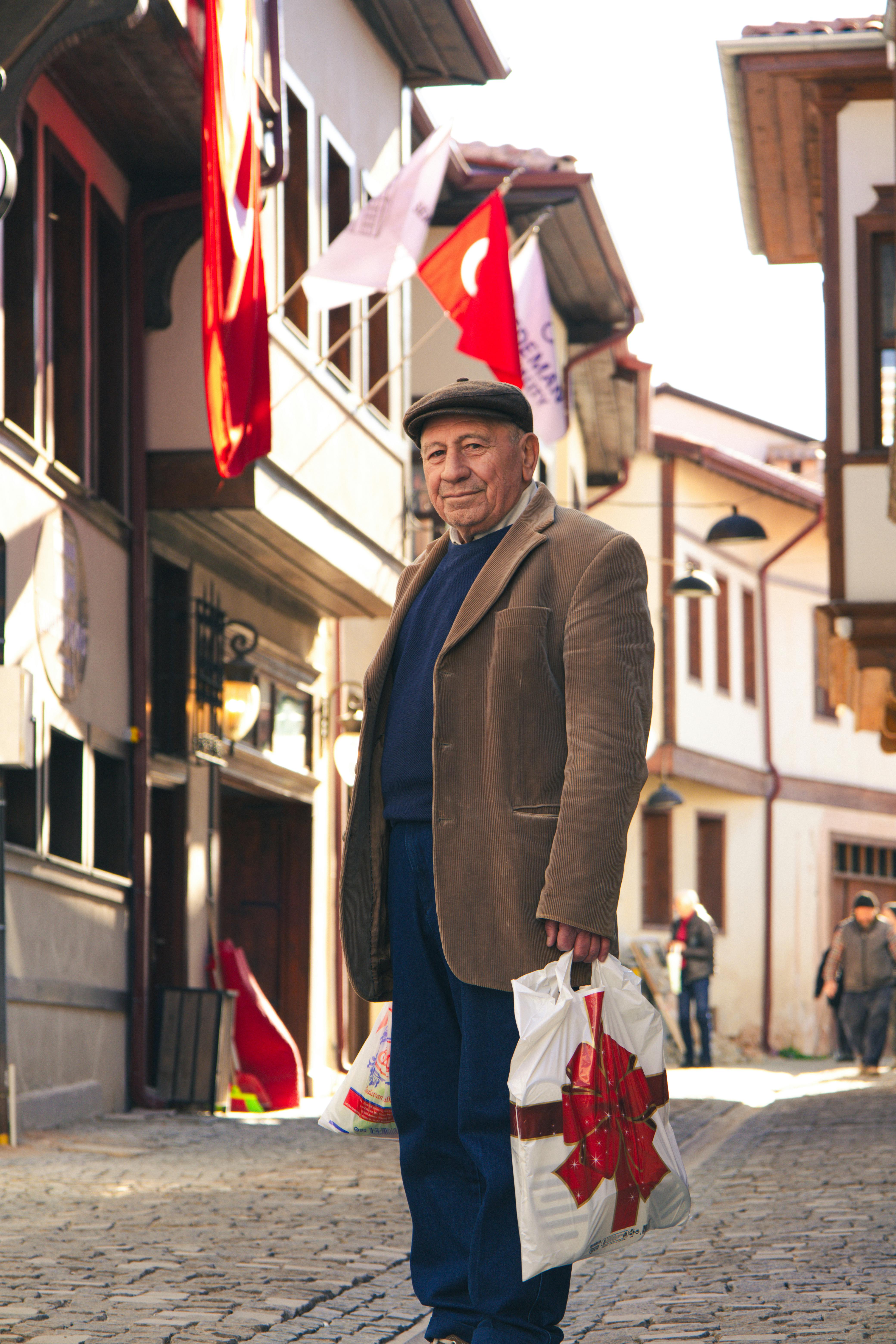 免费 在明亮的日光下，一位老人走在土耳其屈塔希亚的一条历史悠久的街道上。 素材图片