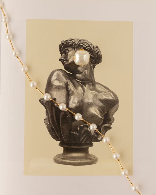 Free Black and white sculpture art contrasted with a modern pearl necklace. Stock Photo