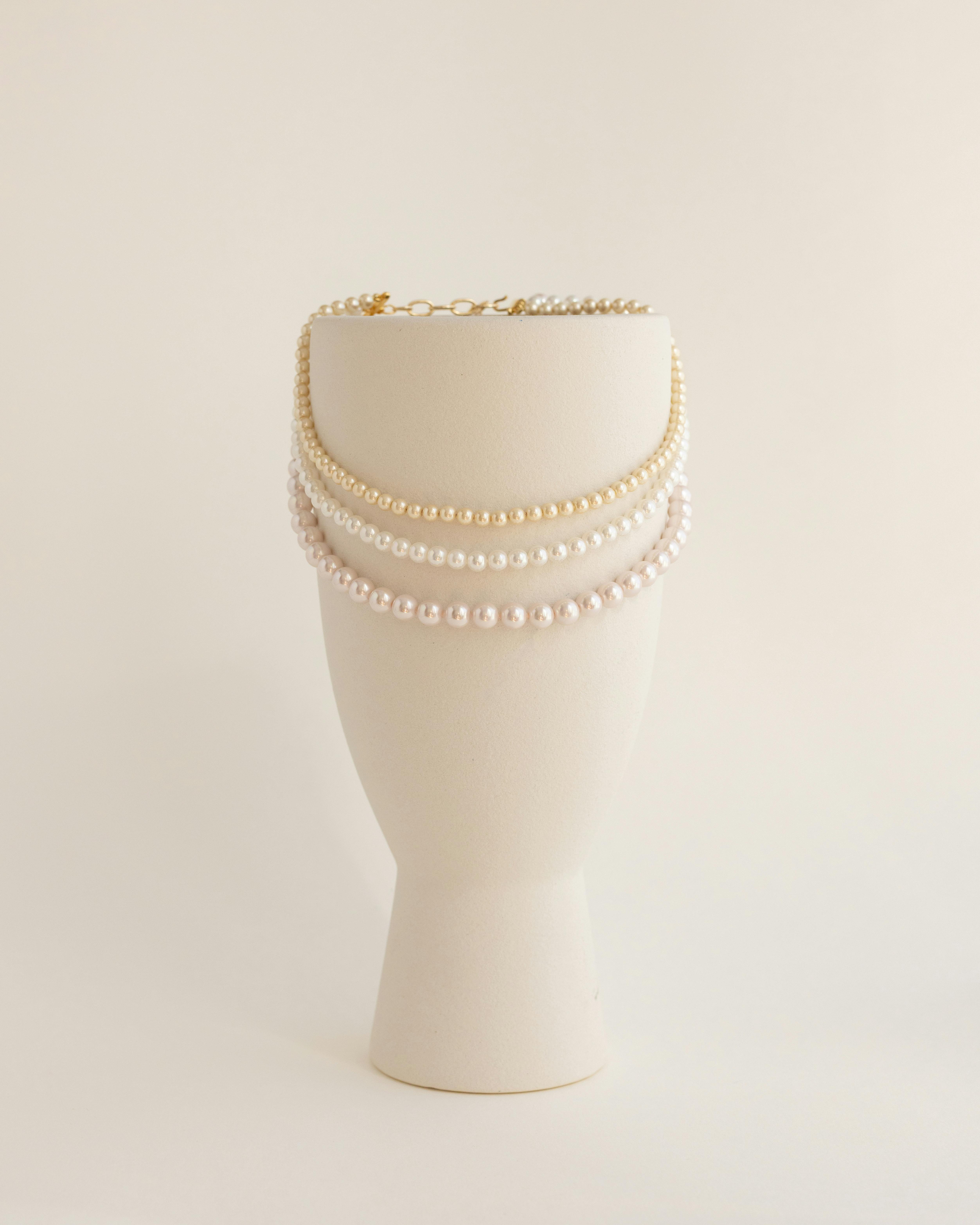 免费 精致的珍珠项链优雅地垂挂在简约的奶油色支架上，非常适合用来展示珠宝。 素材图片