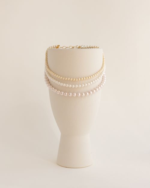 Free Sophisticated pearl necklaces elegantly draped over a minimalist cream stand, perfect for jewelry showcases. Stock Photo