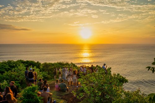 Free Group of adults enjoying a vibrant sunset by the ocean in Bali, Indonesia. Stock Photo