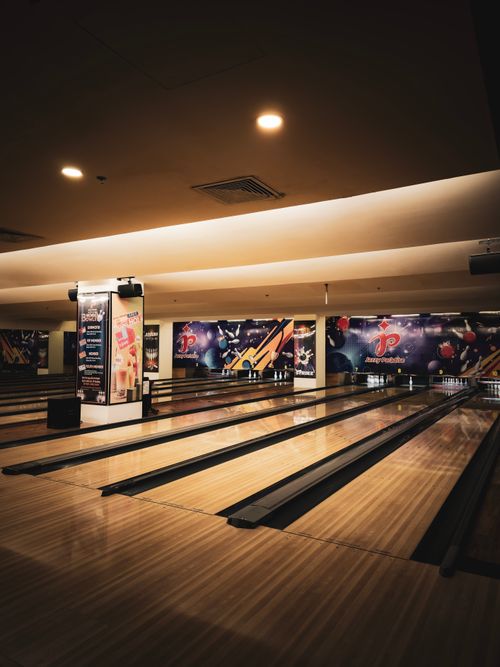 Free A dimly-lit bowling alley featuring multiple lanes and neon decorations creating a fun atmosphere. Stock Photo