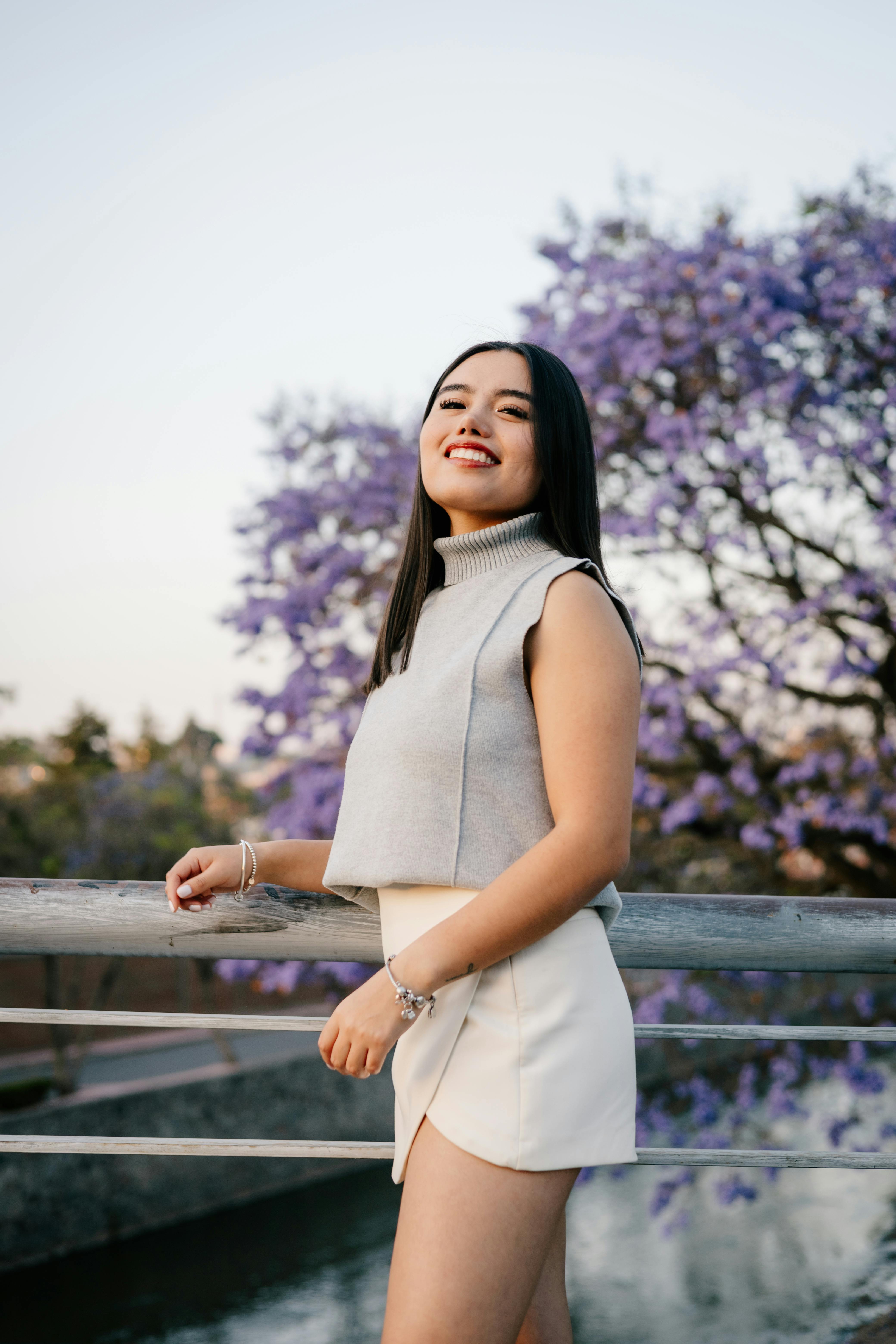 Zadarmo Mladá žena stojaca na moste s kvitnúcimi jacarandami. Fotka z fotobanky