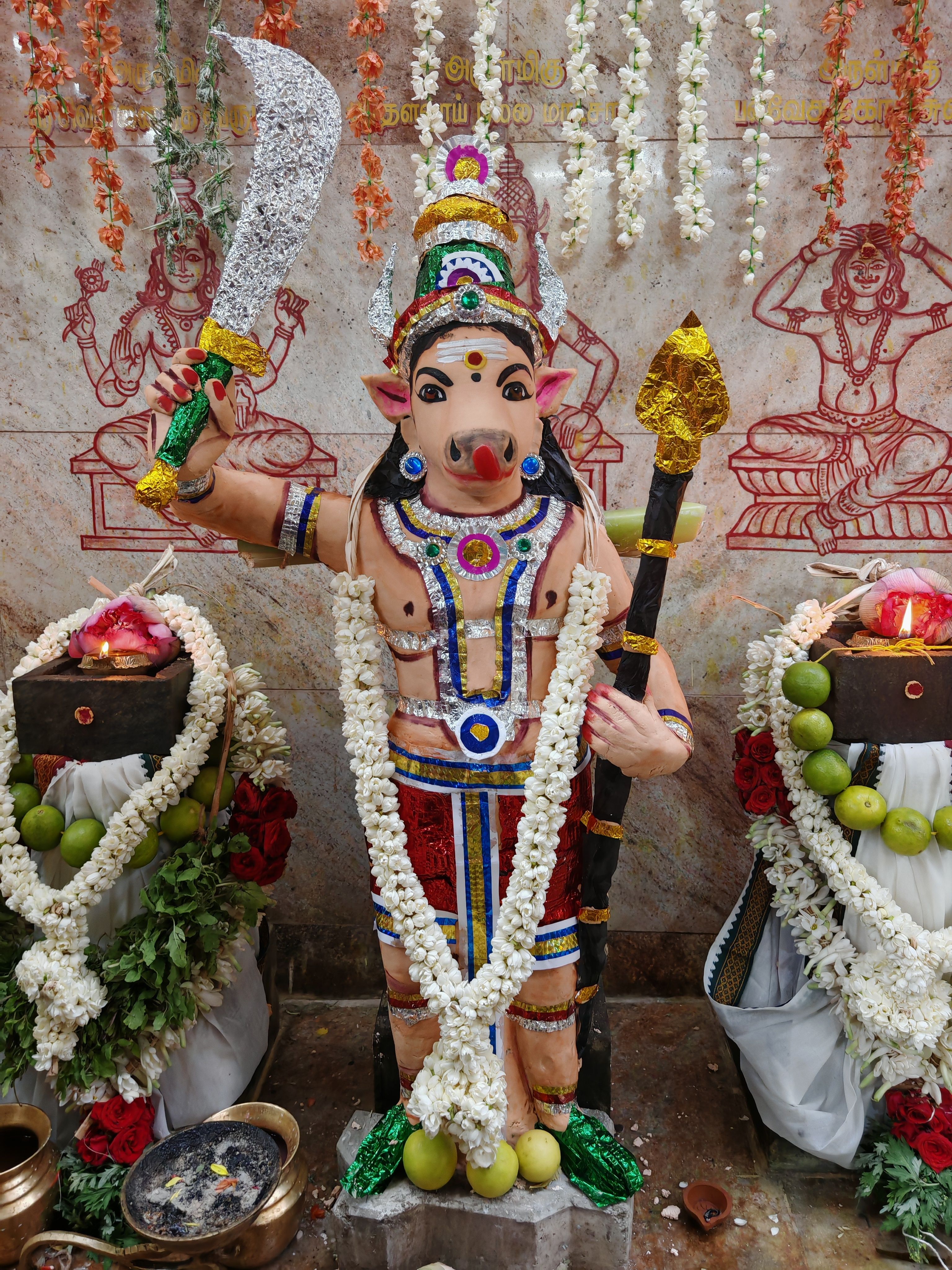 Vibrant statue of the Hindu deity Varaha adorned with flowers and offerings at a temple in Sivakasi, India.