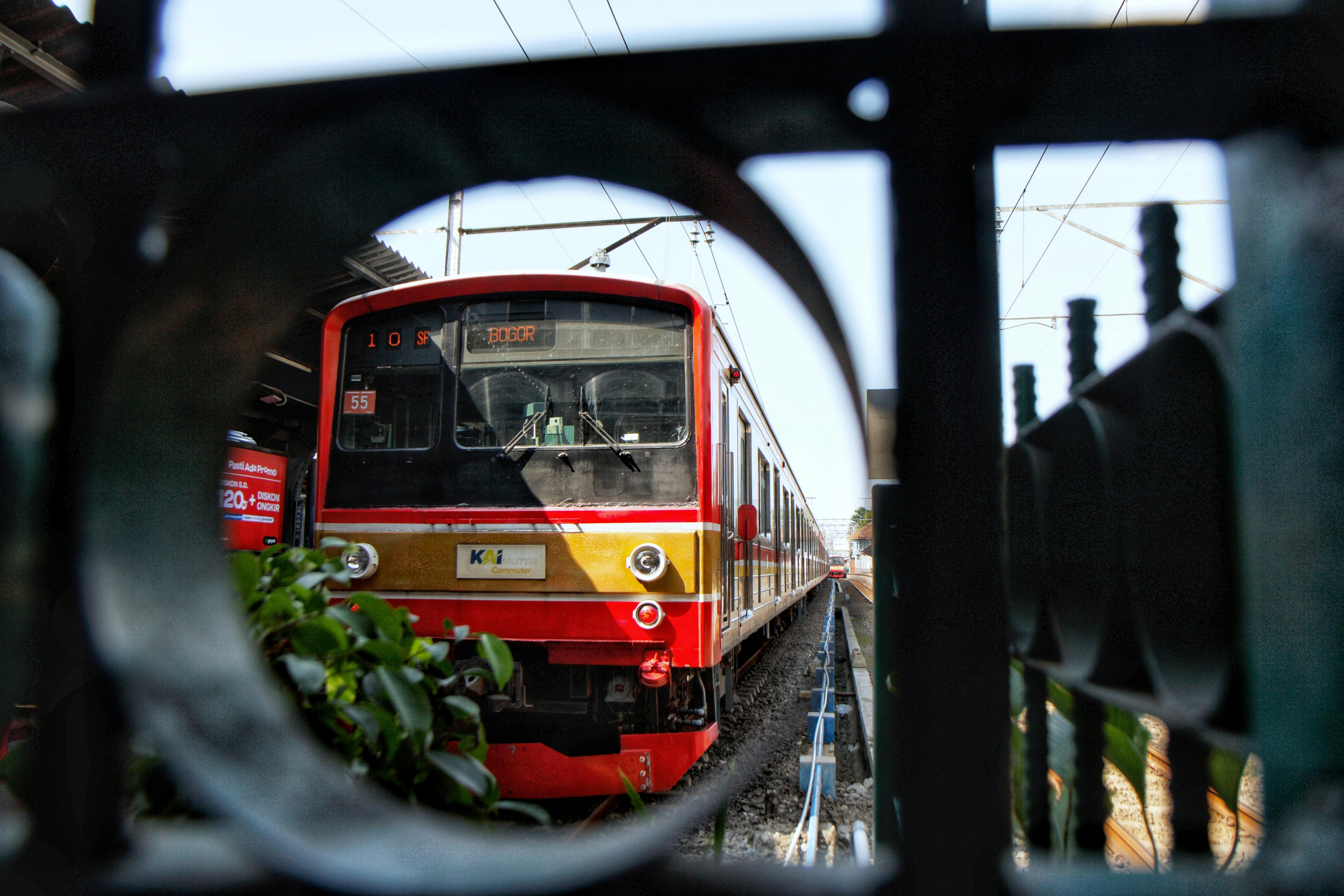 免费 一列红色通勤列车抵达车站的特写镜头，画面被金属栏杆框住。 素材图片