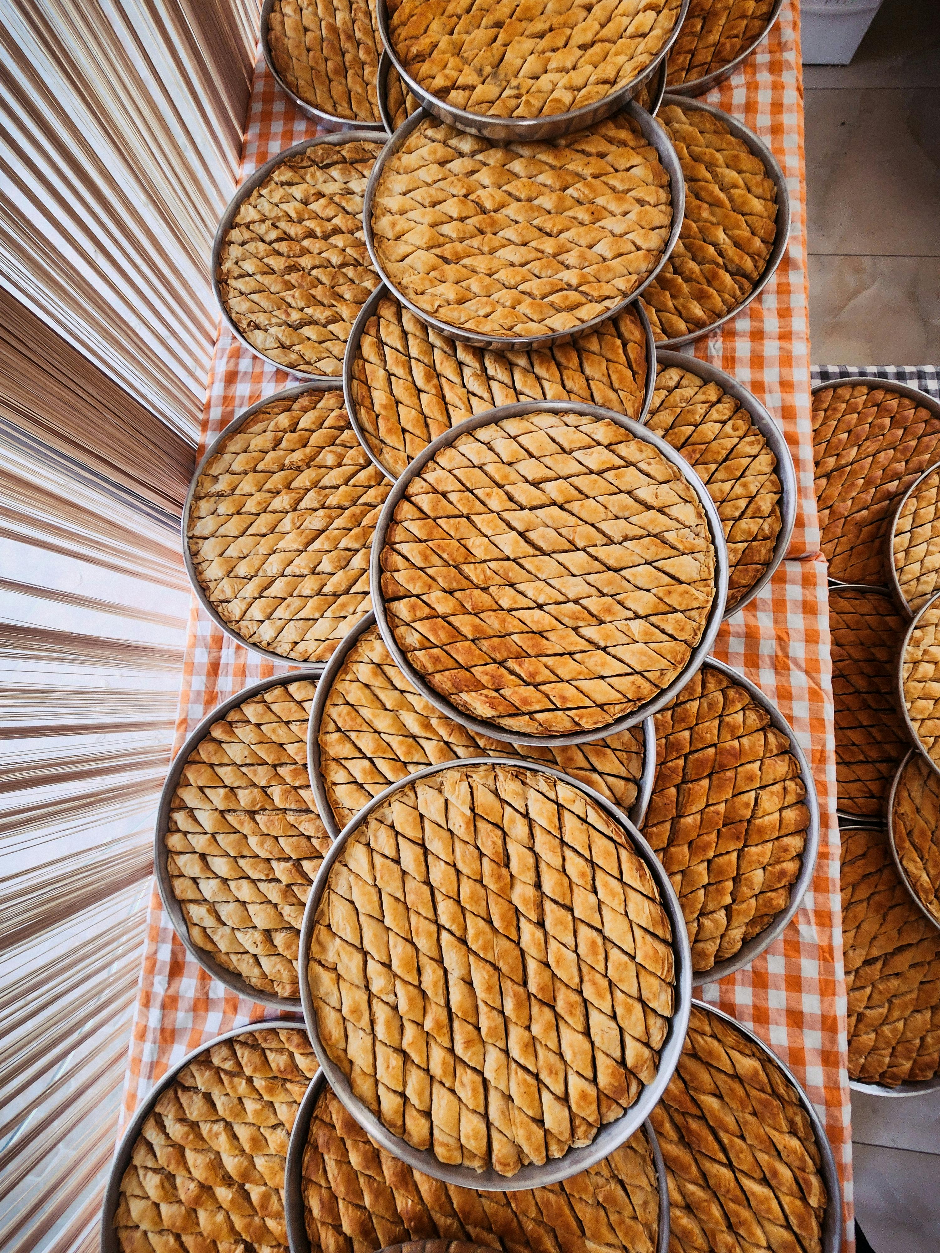 免费 从上方俯视，桌子上摆放着多个圆形土耳其果仁蜜饼，展现出错综复杂的格子图案。 素材图片