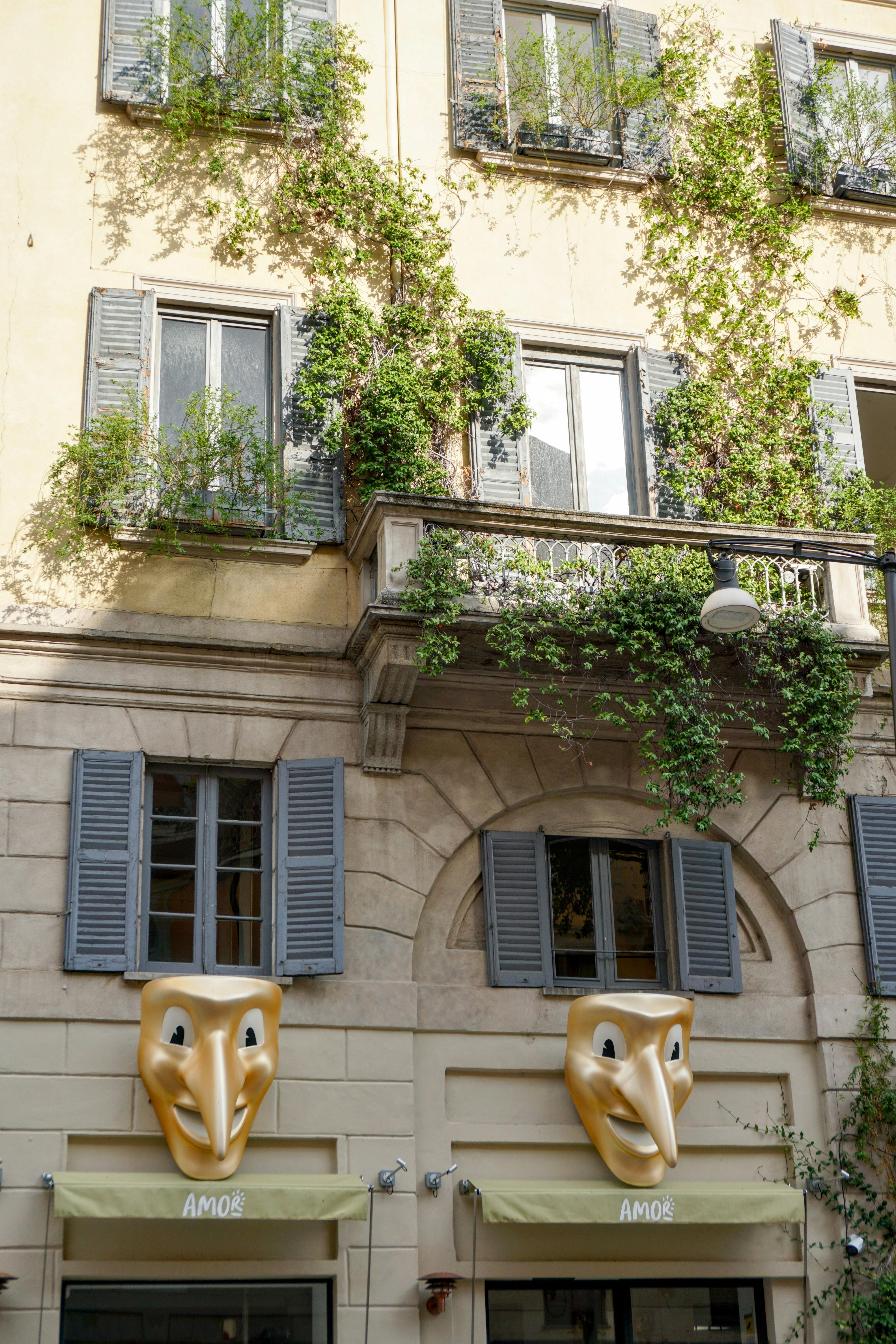 免费 米兰迷人的外立面，爬满常春藤，饰有独特的面部雕塑，展现了经典的意大利建筑风格。 素材图片