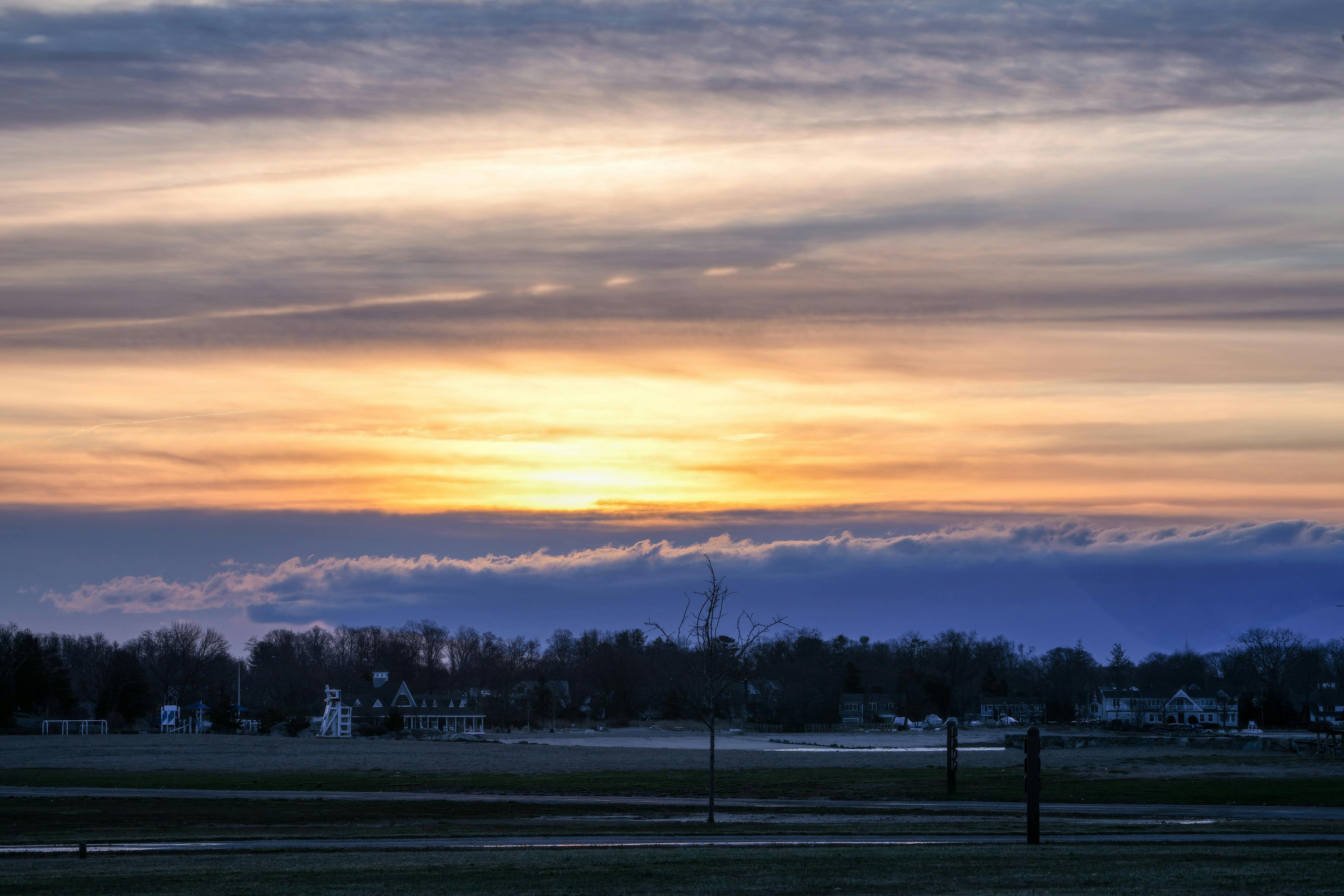 Miễn phí Cảnh hoàng hôn yên bình buổi tối với những sắc màu rực rỡ chiếu sáng những ngôi nhà và cánh đồng ngoại ô. Ảnh lưu trữ