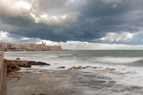 Free A stunning view of Vieste's coastline under dramatic clouds and serene ocean waves. Stock Photo
