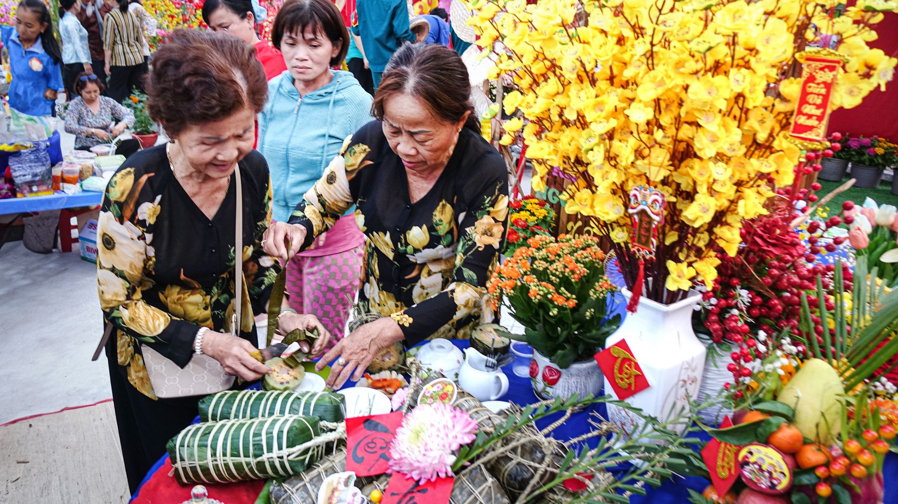 Người cao tuổi chuẩn bị các món ăn truyền thống tại một lễ hội Việt Nam rực rỡ với hoa.
