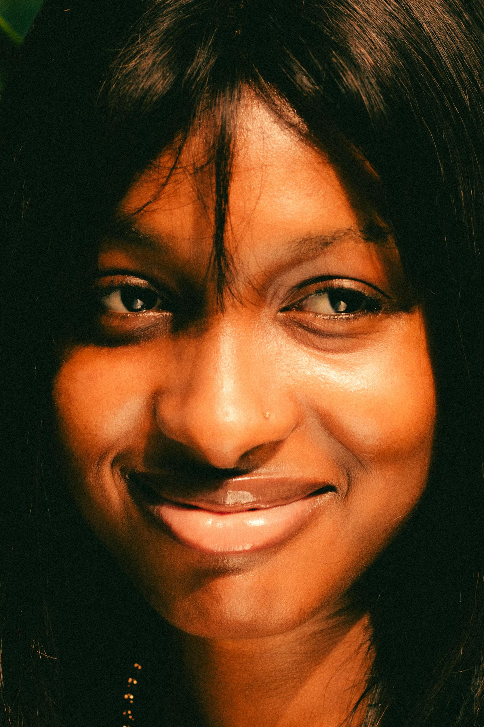 무료 자연광을 활용하여 여성의 따뜻한 미소와 표현력 풍부한 눈빛을 강조한 클로즈업 인물 사진. 스톡 사진