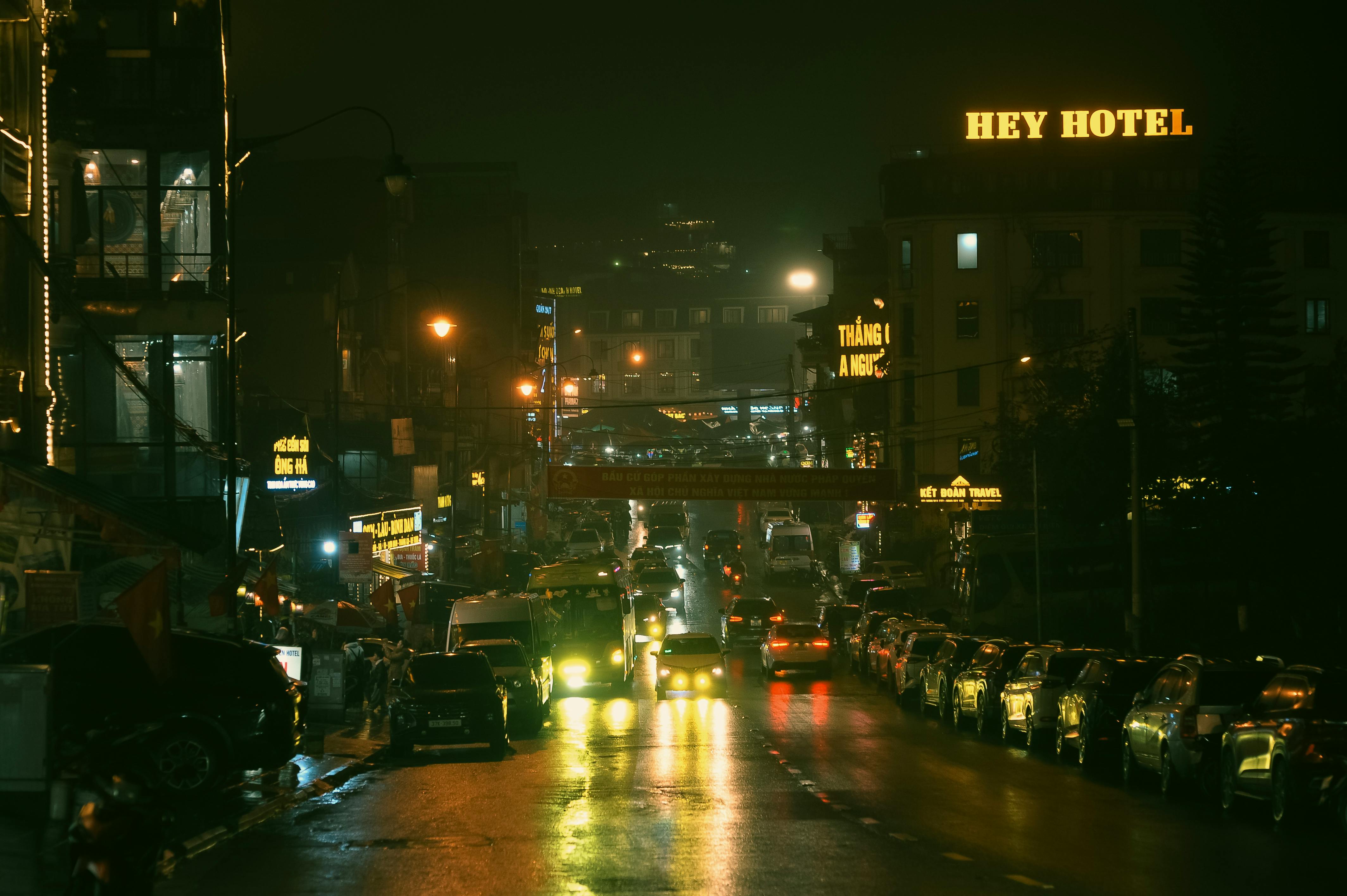 ฟรี ภาพบรรยากาศเมืองยามค่ำคืนที่ดูหม่นหมอง มีรถยนต์ ไฟถนน และป้ายโรงแรมเฮย์ คลังภาพถ่าย