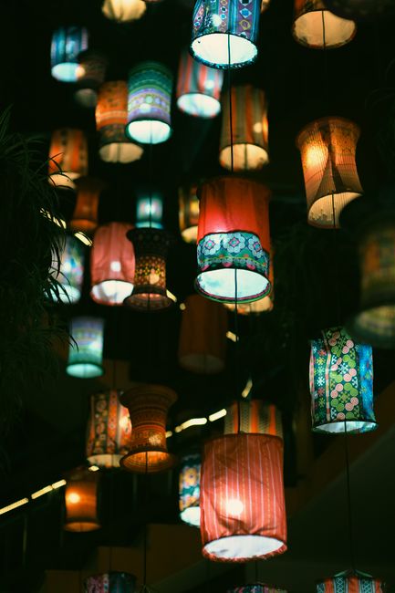 A vibrant display of various patterned hanging lanterns illuminating a night event.