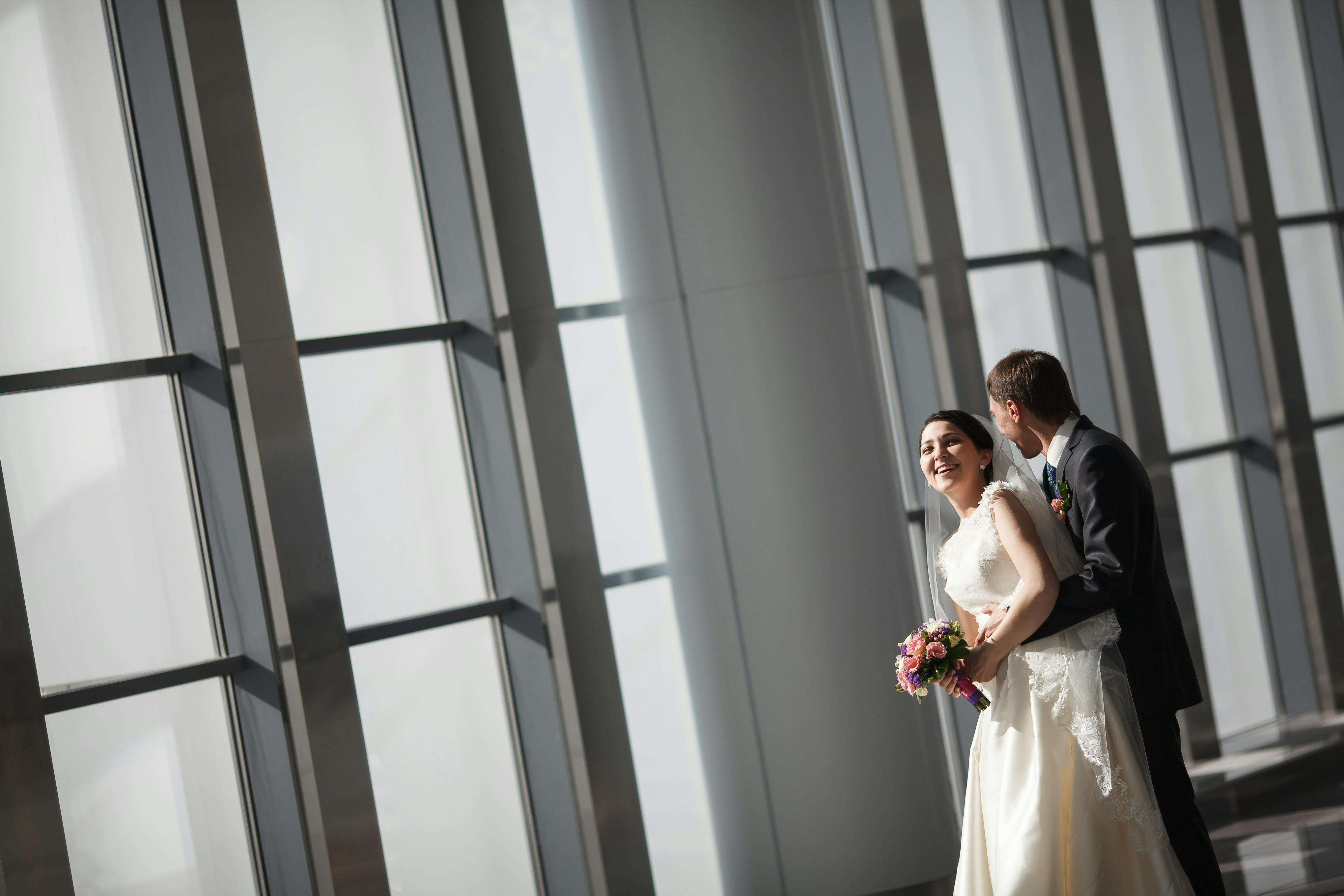 免费 幸福的新郎新娘在室内享受着自然光和优雅的婚礼环境。 素材图片