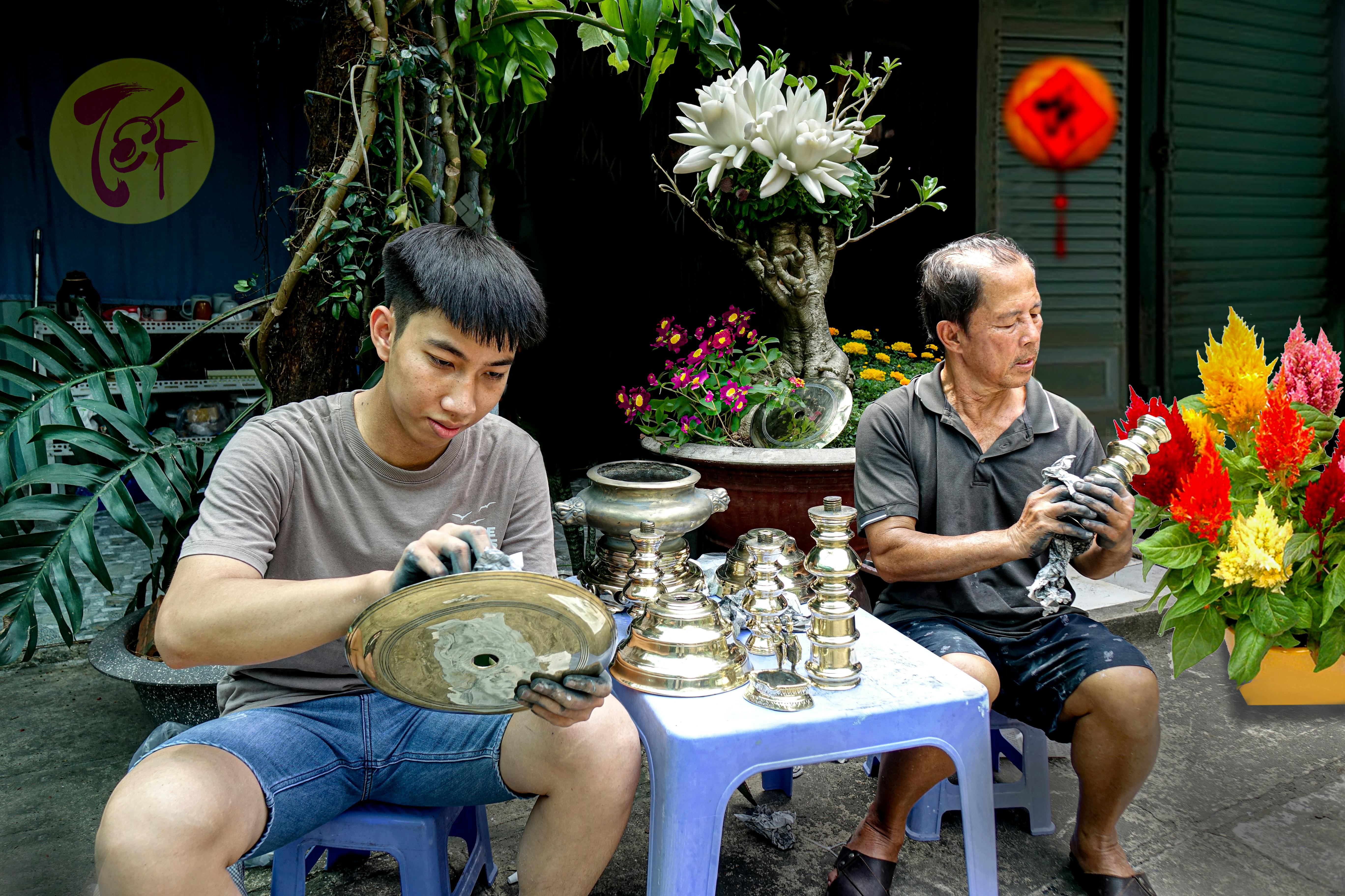 免费 两位工匠在绿树鲜花环绕的生机勃勃的户外环境中，认真地打磨着金属工艺品。 素材图片