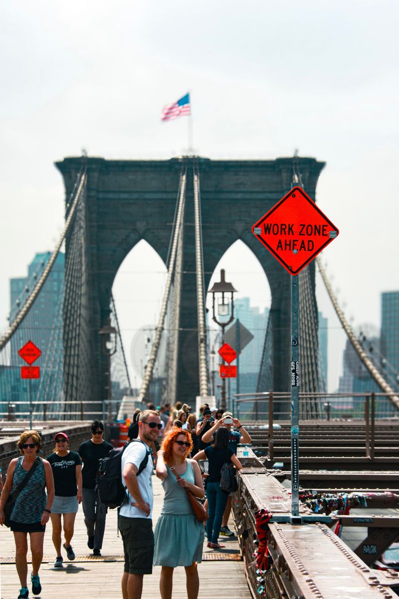 Pedestrians walking across the Brooklyn Bridge with its stone towers and cables