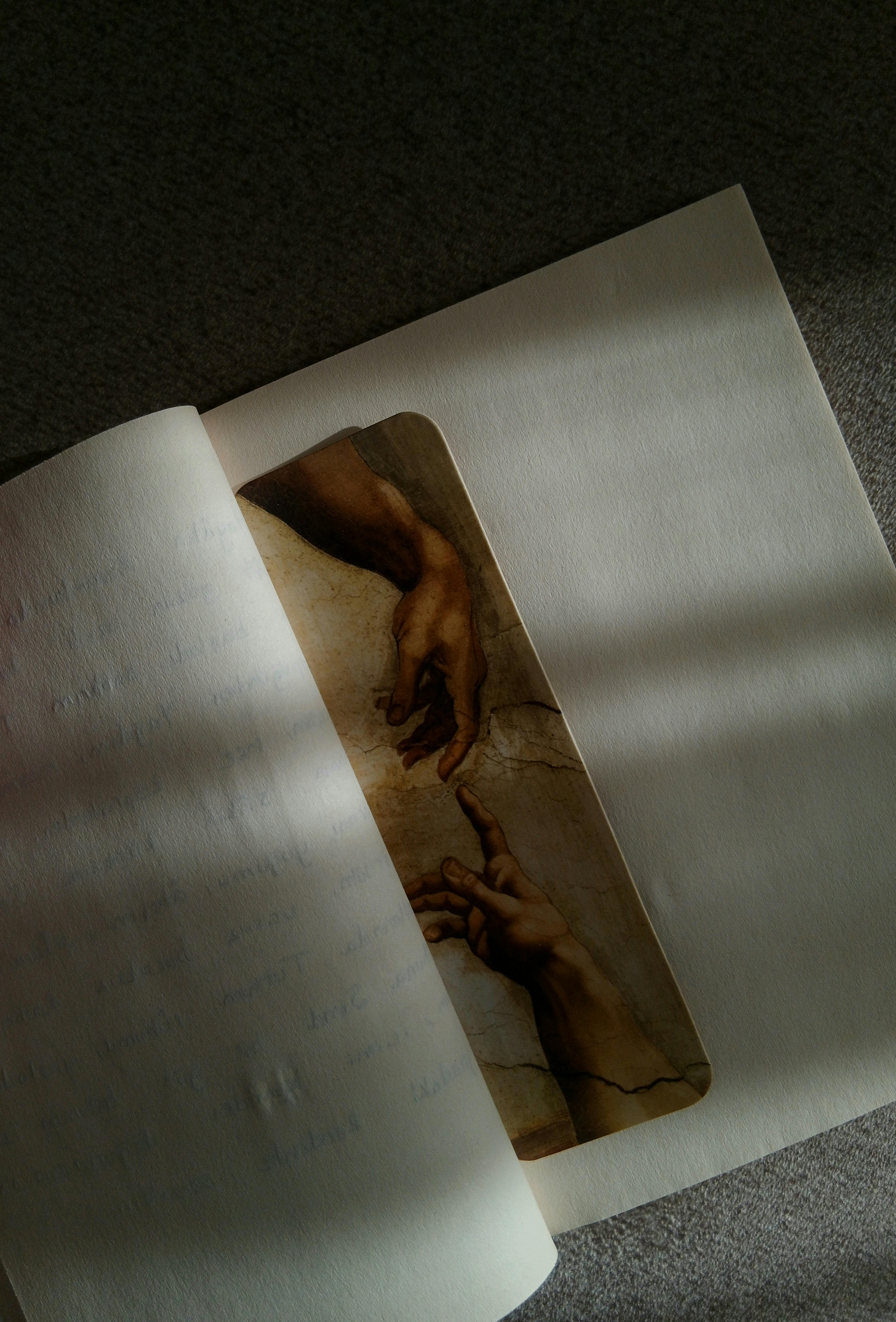 免费 在自然光下，纸上对《创造亚当》这幅画作进行了富有创意的描绘。 素材图片