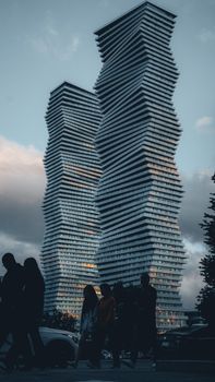 Silhouetted people walk past striking modern towers in Mississauga, Ontario.