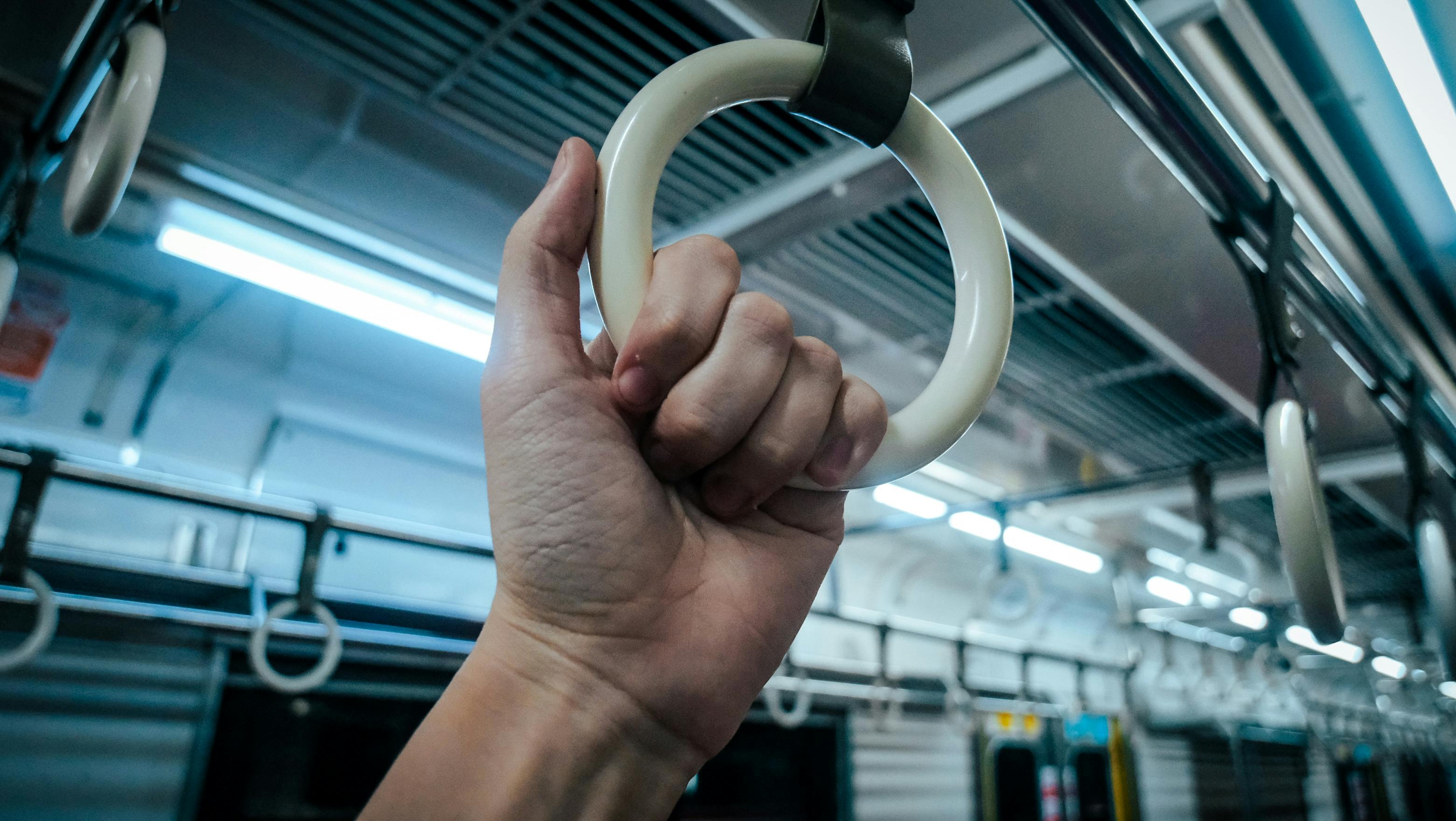 Kostenlos Nahaufnahme einer Hand, die in einer U-Bahn einen Haltegriff umfasst, wodurch die Bedeutung des öffentlichen Nahverkehrs hervorgehoben wird. Stock-Foto