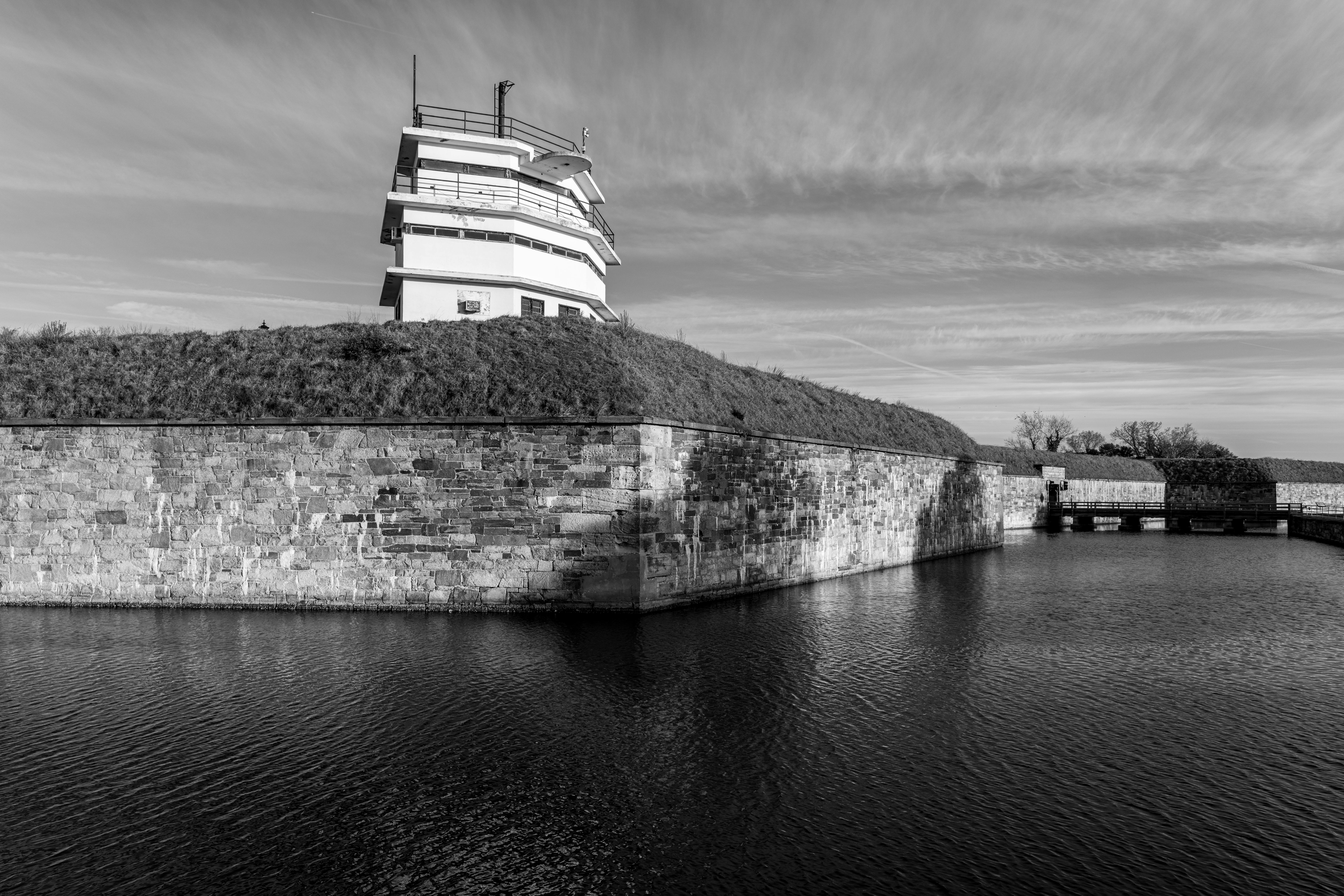 ฟรี ภาพถ่ายขาวดำของป้อมมอนโรว์ในแฮมป์ตัน รัฐเวอร์จิเนีย แสดงให้เห็นถึงสถาปัตยกรรมทางประวัติศาสตร์และผืนน้ำอันเงียบสงบ คลังภาพถ่าย