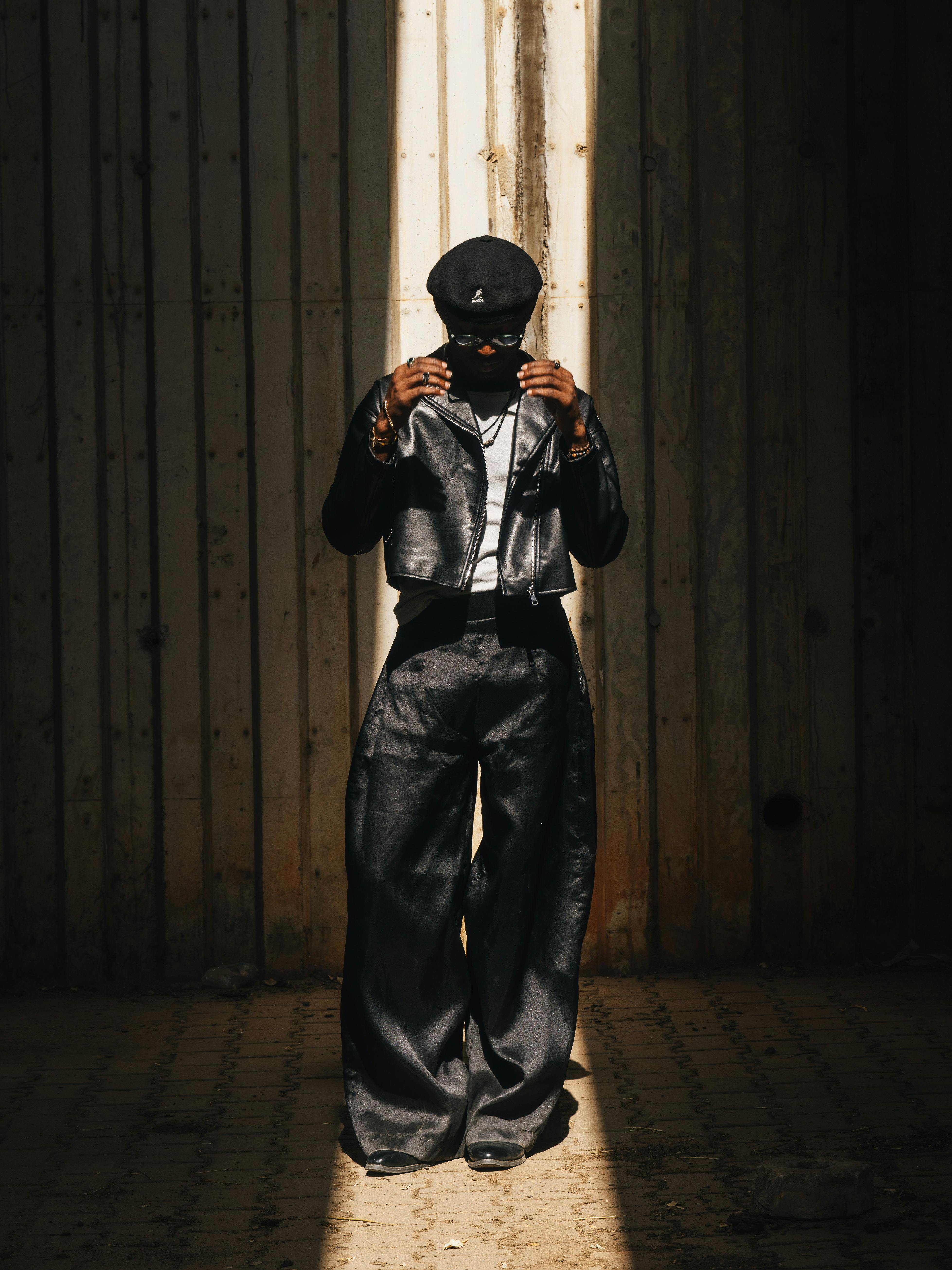 ingyenes Egy divatos, stílusos ruhát viselő személy drámai megvilágításban áll, árnyékokat vetve. Stockfotó