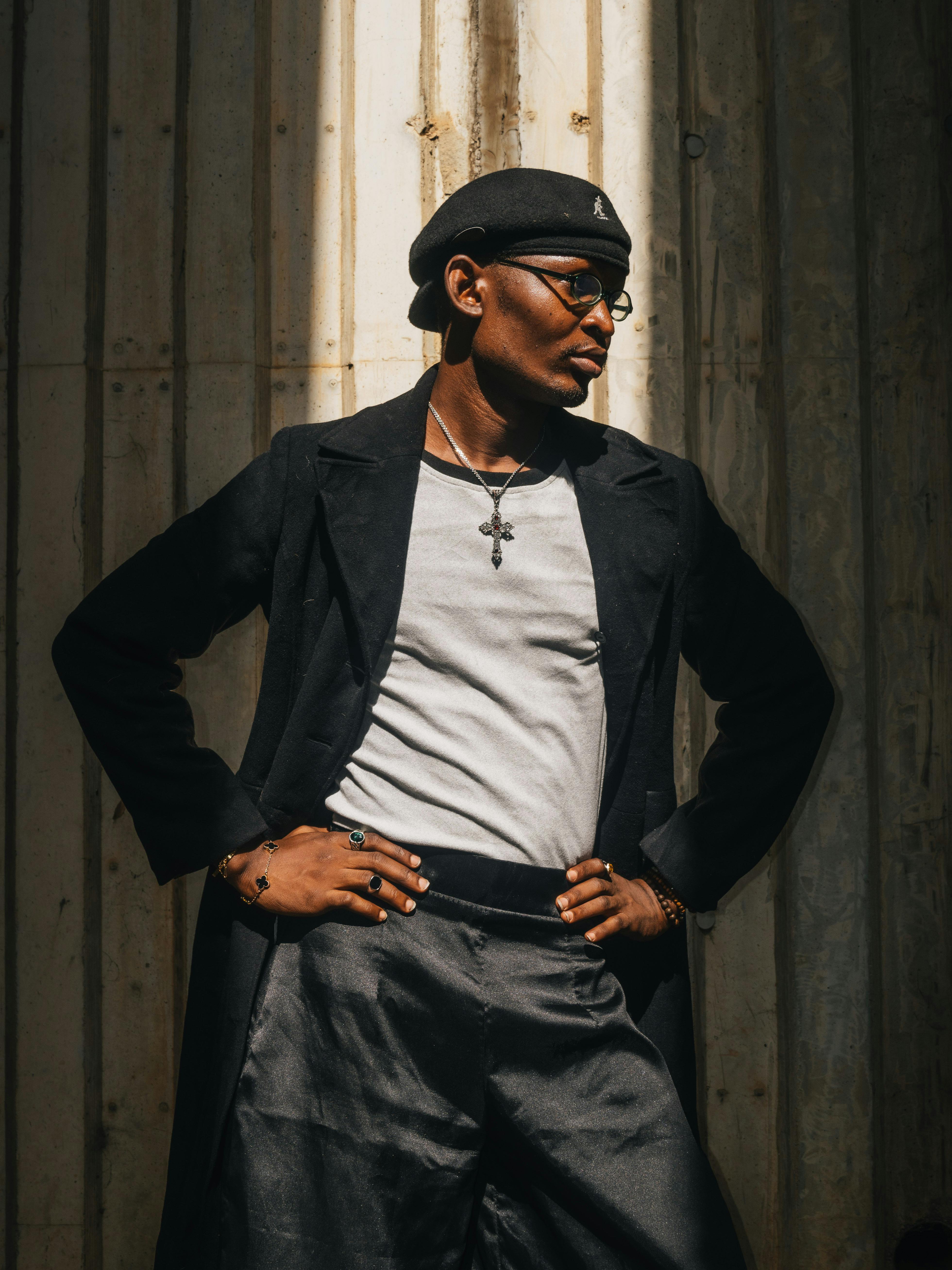 免费 一位戴着贝雷帽、自信满满的男士在阳光下摆姿势，投下浓重的影子。 素材图片