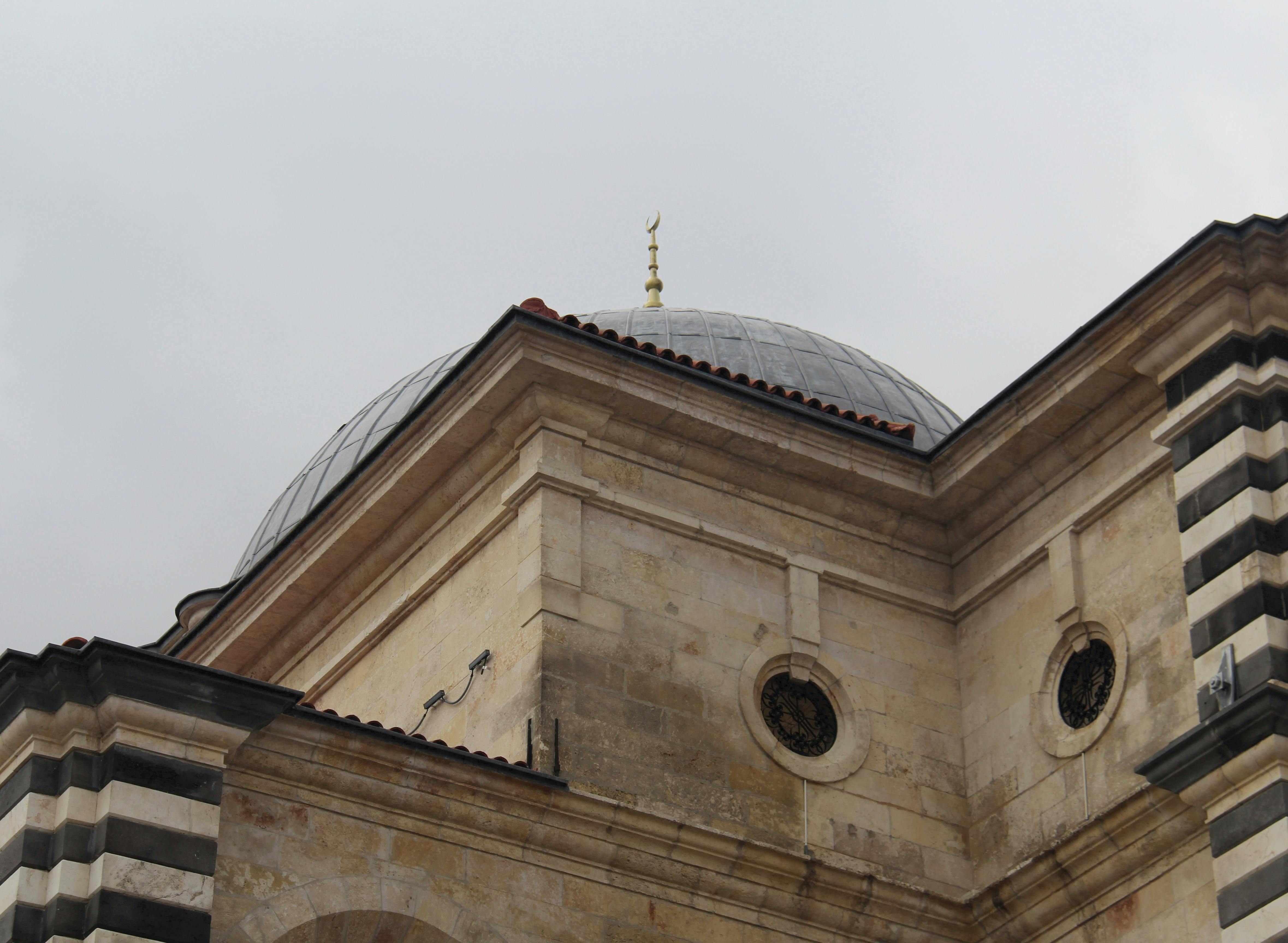 ฟรี ภาพระยะใกล้ของสถาปัตยกรรมโดมประดับประดาอย่างวิจิตรงดงามด้วยรายละเอียดหิน ภายใต้ท้องฟ้าที่ปกคลุมไปด้วยเมฆ คลังภาพถ่าย