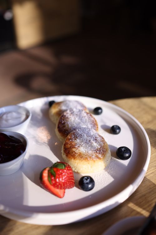 Free Appetizing pancakes dusted with sugar, accompanied by strawberries, blueberries, and sauces. Stock Photo