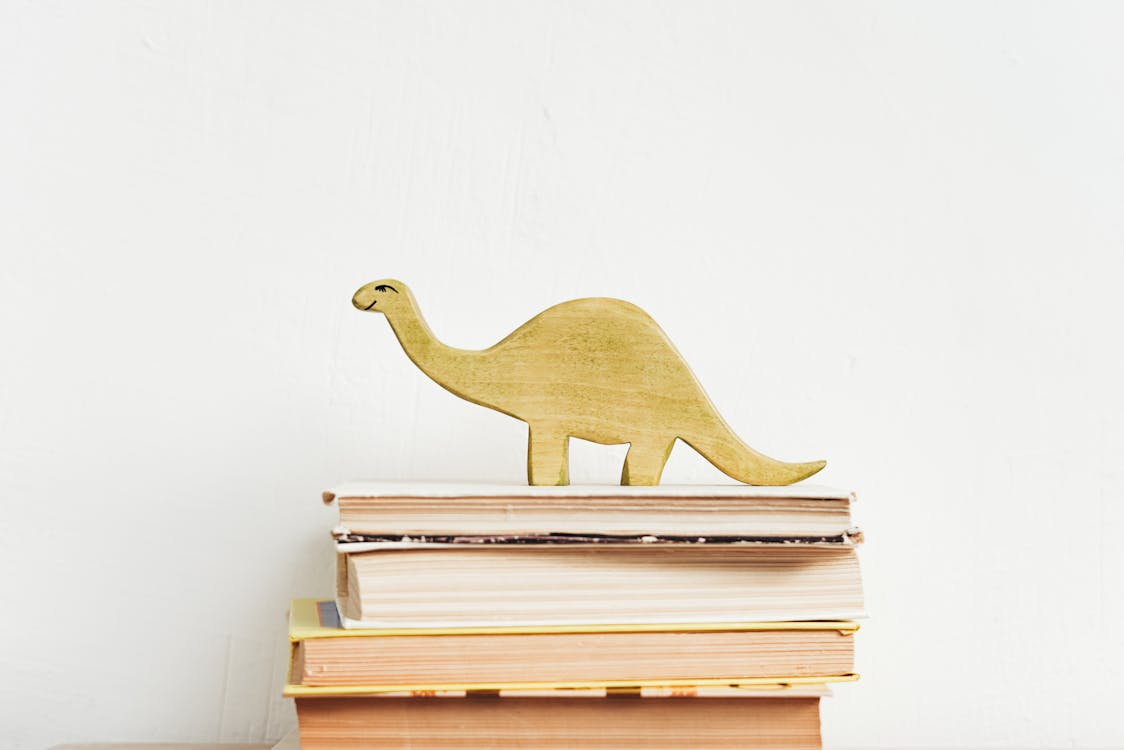 Free Brown Wooden Dinosaur Figurine on White Book Stock Photo