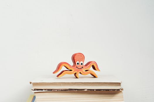 Charming octopus wooden toy perched on a stack of books, exuding charm and creativity.