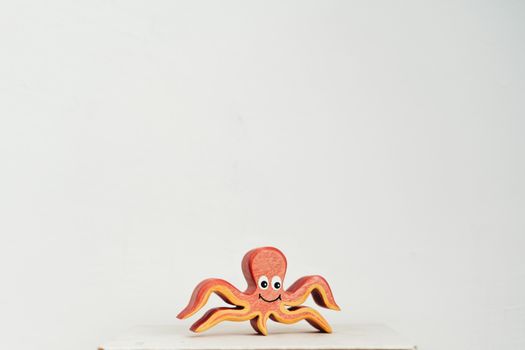 Cute wooden octopus toy with a smiling face on a clean white background.