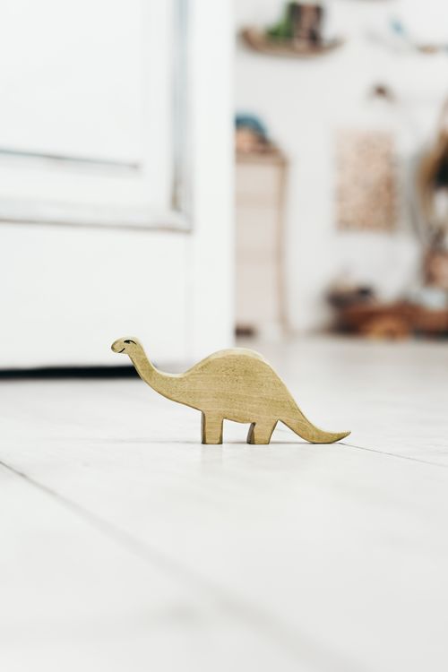 Free Minimalist wooden dinosaur toy on a bright floor, perfect for kids' playrooms. Stock Photo