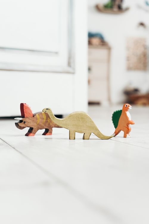 Free A lineup of colorful wooden dinosaur toys on a light wooden floor in a playroom. Stock Photo