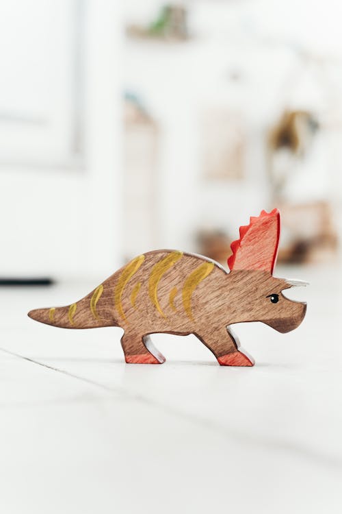 Фигурка коричневого и красного динозавра на полу