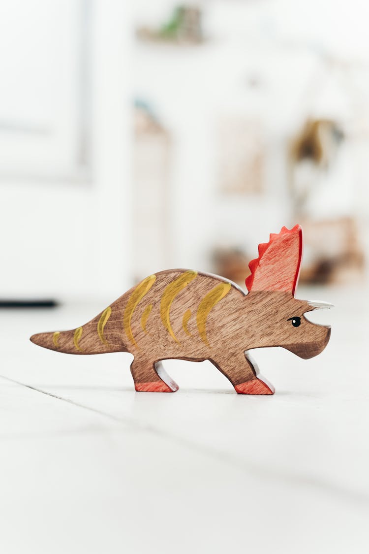 Brown And Red Dinosaur Figurine On The Floor