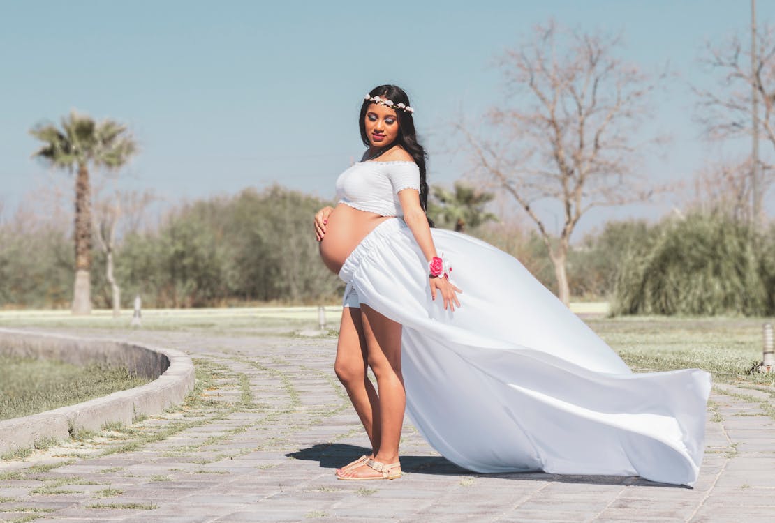 Pregnant Woman in White Dress Standing on Gray Concrete Road