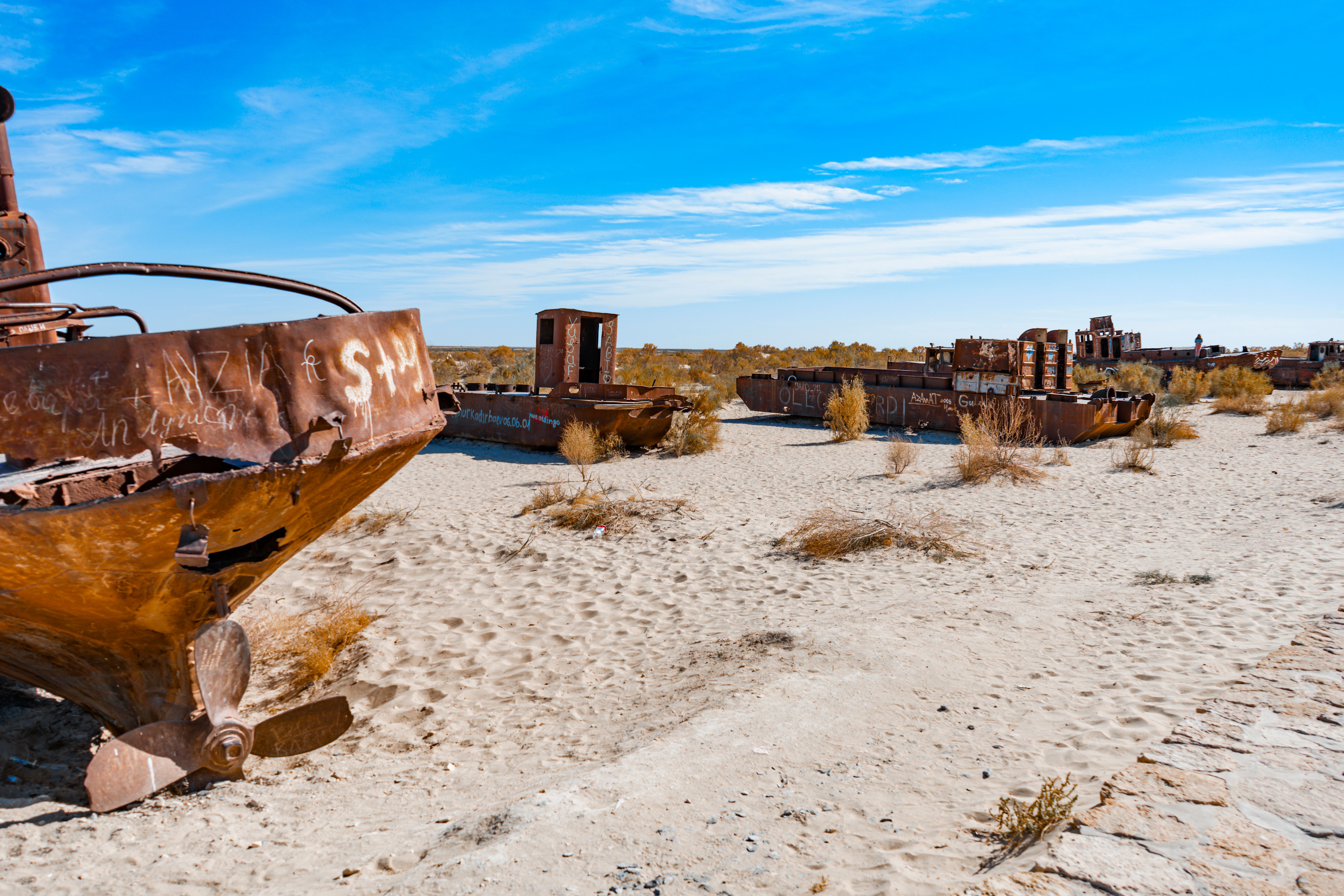 Abandoned rusty ships stranded on the dry Aral Sea bed in Uzbekistan, showcasing desertification.