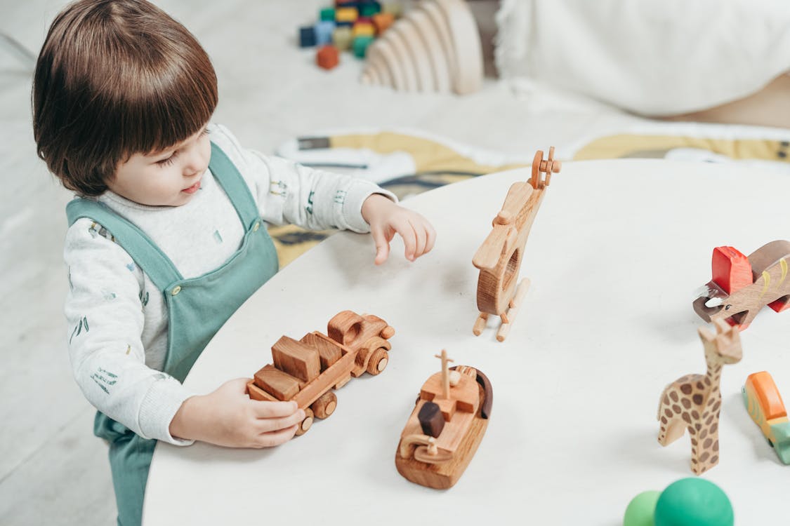 Free Boy in White and Green Long Sleeve Shirt Playing Brown Wooden Toys Stock Photo