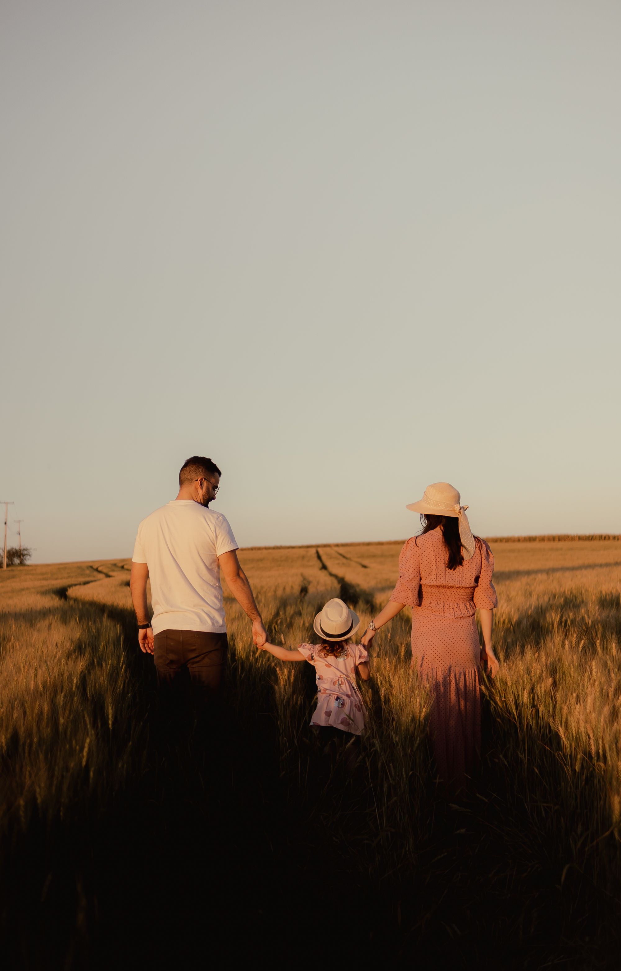 Famiglia che cammina nel grano al tramonto
