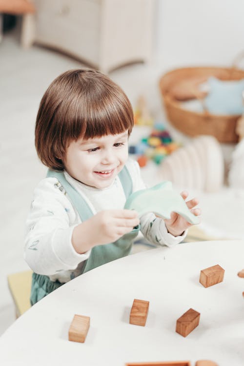 Free Child in White Long Sleeve Top Playing with Toys Stock Photo