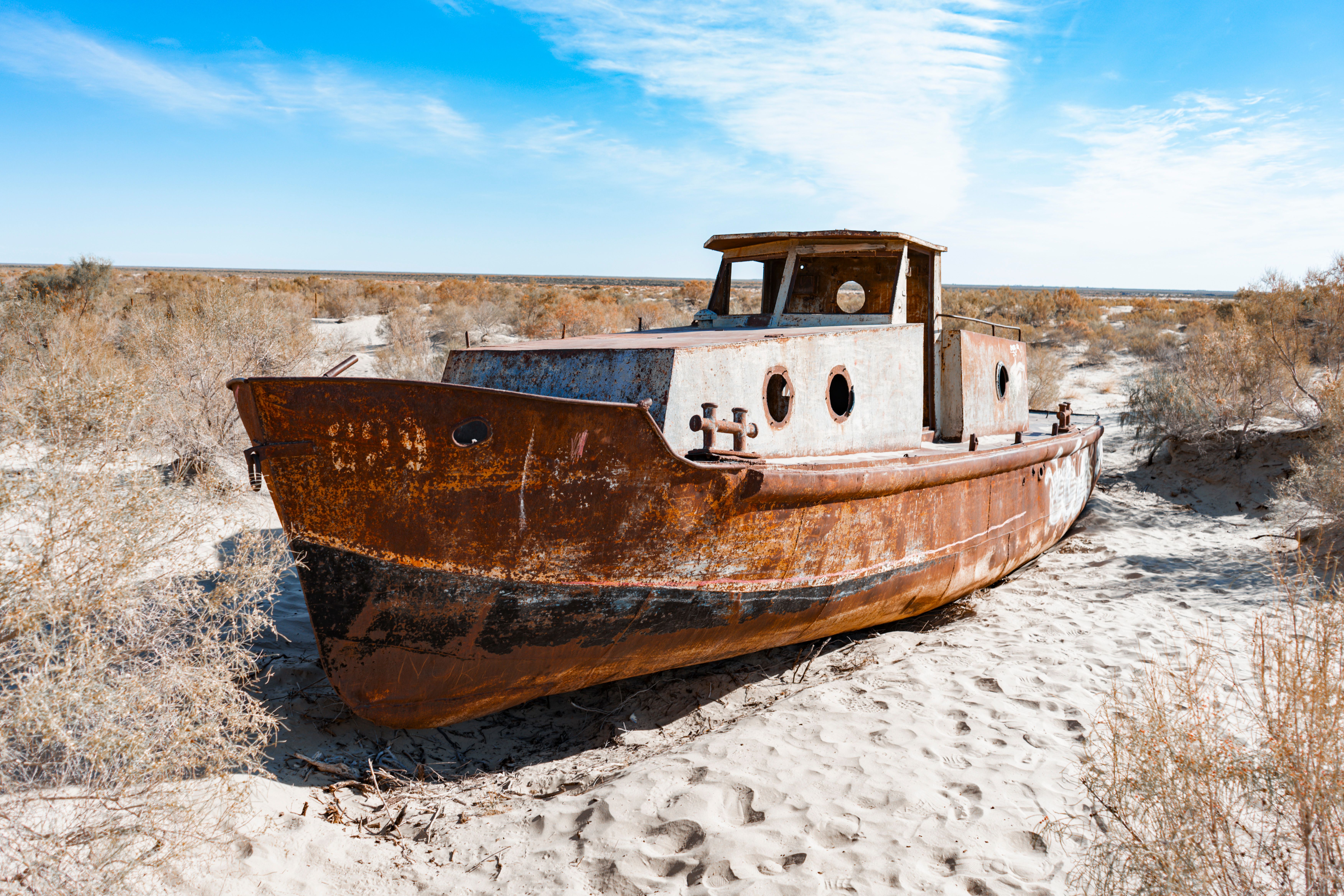 Abandoned rusty ship stranded in the sands of the Aral Sea desert in Uzbekistan, symbolizing drought and ecological change.