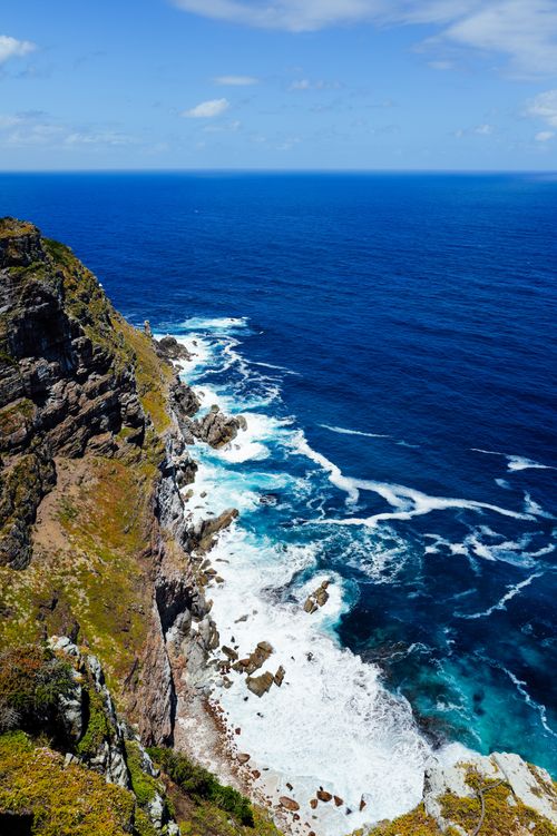 Free Majestic ocean cliff with clear blue sky and turquoise waves crashing below. Stock Photo